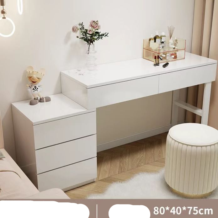 White vanity table with drawers and a small stool in a room setting.