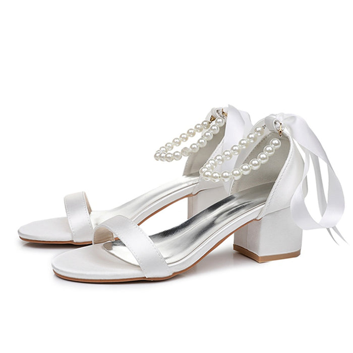 White high-heeled sandals with pearl straps on a white background