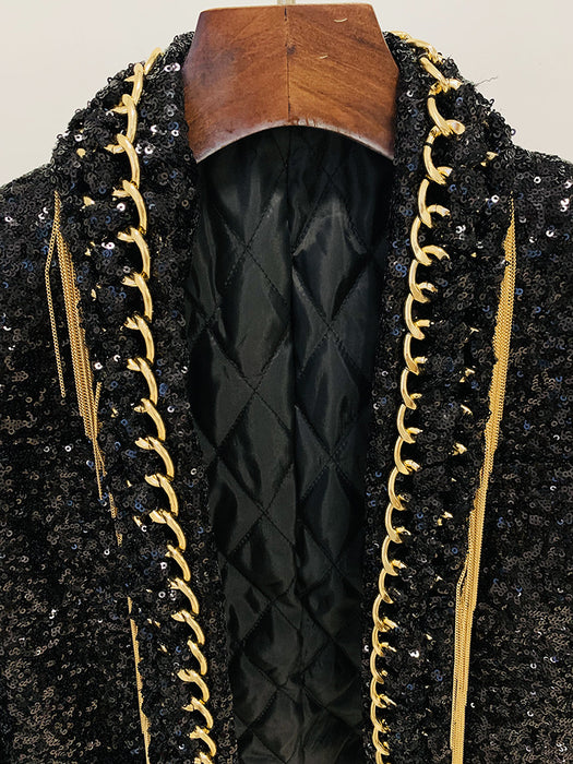 Black sequined garment with gold trim on a wooden hanger against a neutral background