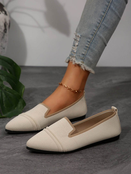 White loafers worn with light blue jeans on a gray surface.