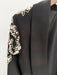 Black garment with gold and white embellishments on a plain background