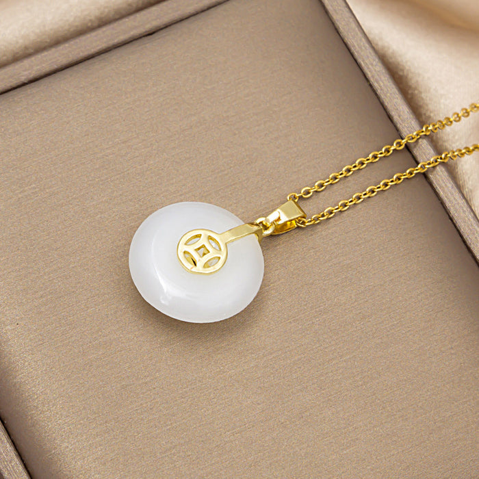 A gold pendant necklace with a round white jade-like disc featuring a gold Chinese character emblem, displayed on a beige jewelry box.