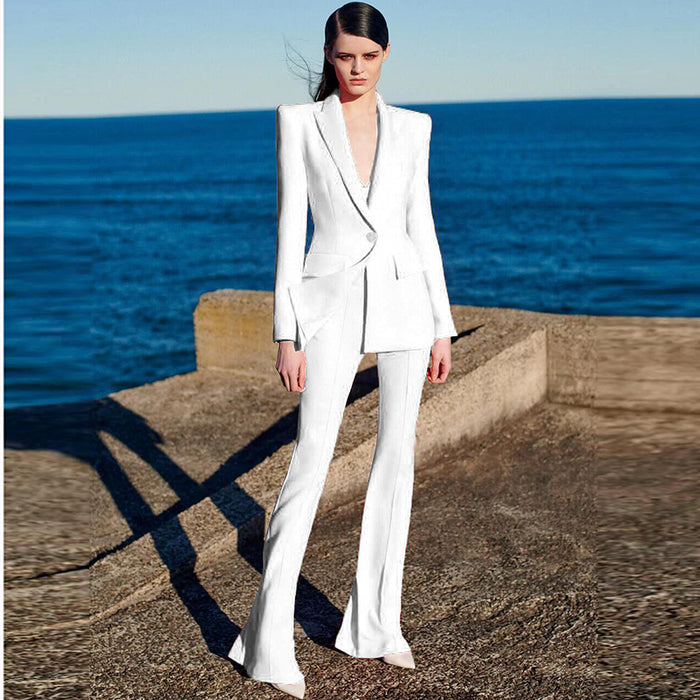 Woman in a white suit standing on a concrete ledge with ocean in the background