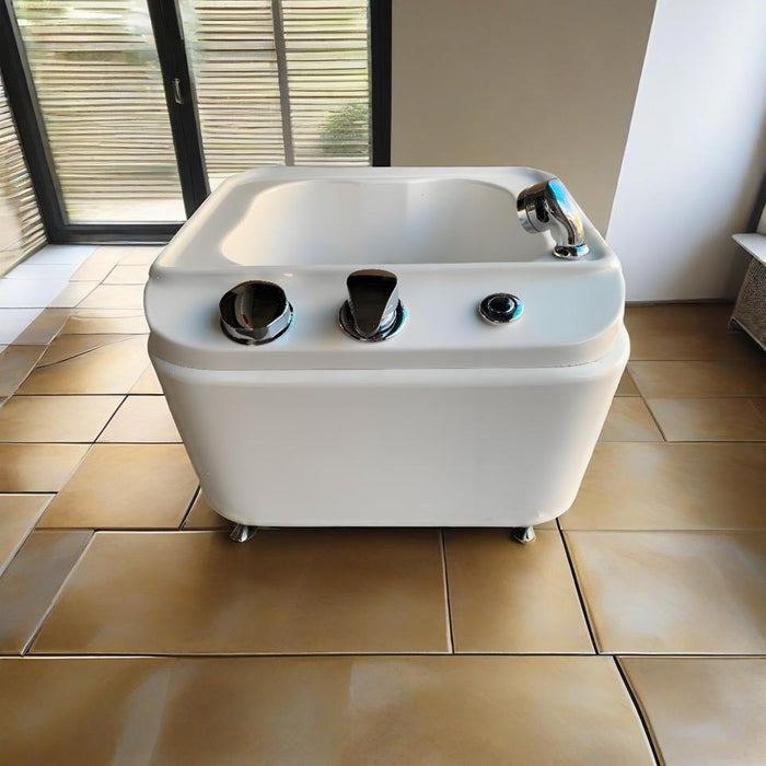 White freestanding bathtub with silver fixtures on a tiled floor