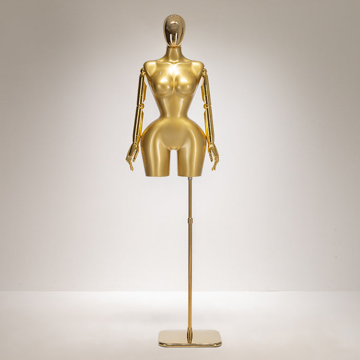 Gold mannequin on a stand against a gray background