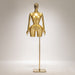 Gold mannequin on a stand against a gray background
