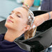 Person getting a hair wash in a salon chair with water splashing.