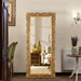 Decorative gold-framed mirror in a room with furniture and decor.