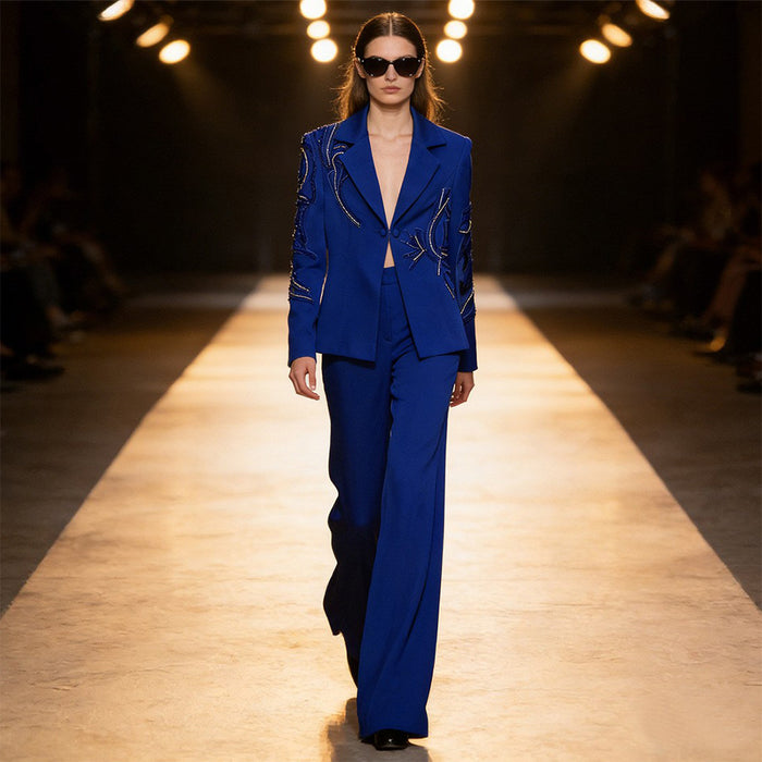 Model wearing a blue suit on a runway with lights in the background