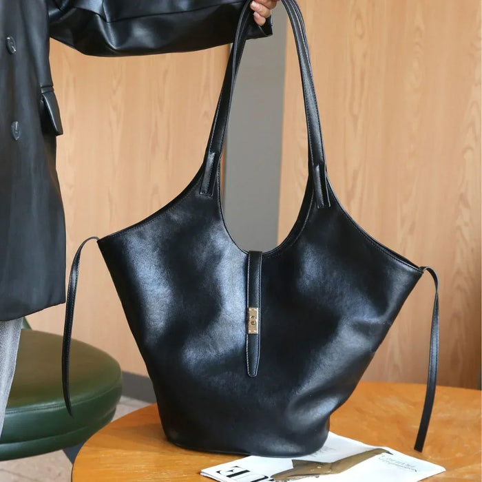 Black leather handbag on a wooden table with a blurred background