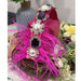 Decorative headband with pink feathers, pearls, and blue gemstones on a floral background.