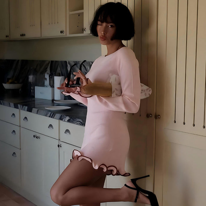 Woman in a pink dress with cat ears standing in a kitchen.