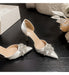 Silver high-heeled shoes with crystal embellishments on a dark surface.