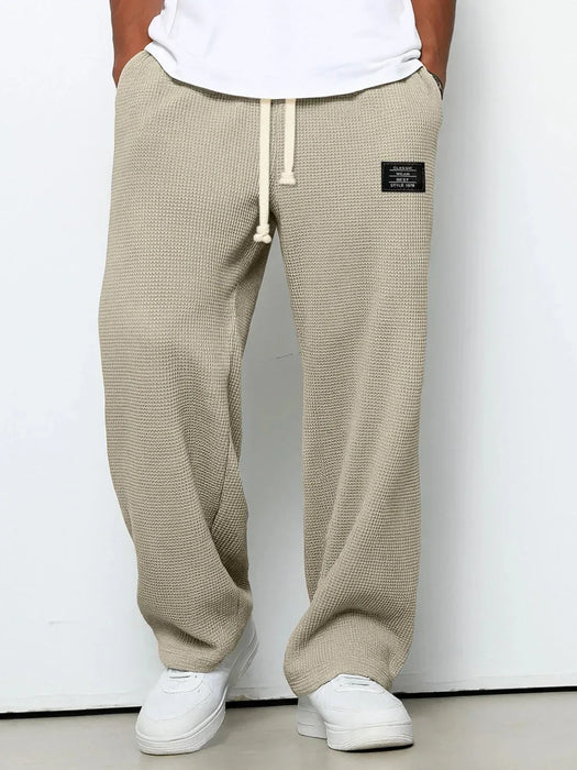 Beige waffle-textured sweatpants with a brand logo on a white background