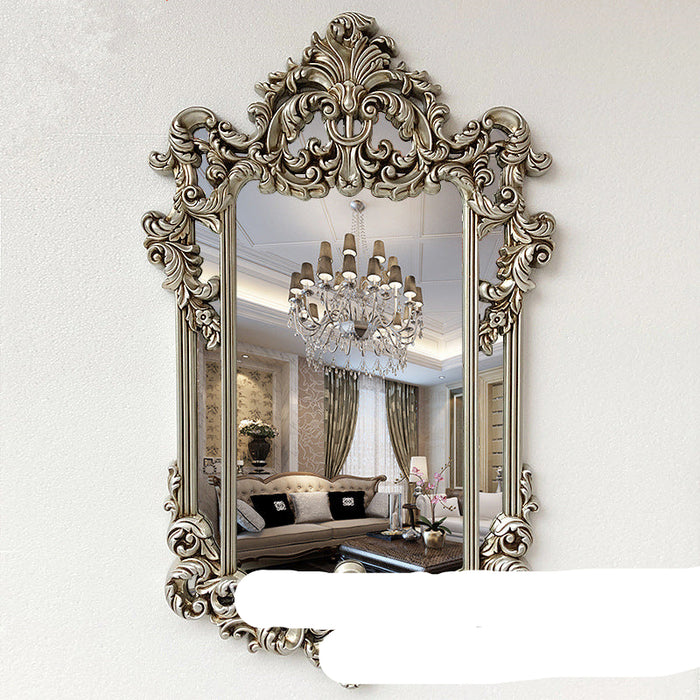 Decorative mirror with intricate gold frame on a white wall