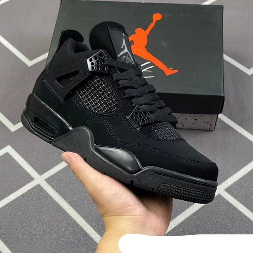 Black sneaker held in hand with Jordan box in the background