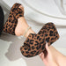 Leopard print platform sandals held by a hand against a white background