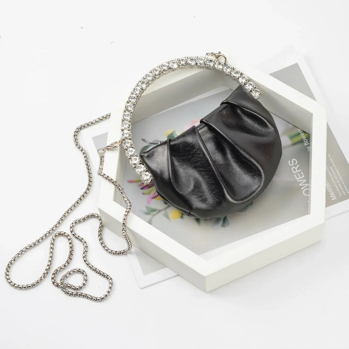 Black handbag with a chain strap on a white surface