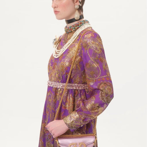Purple and gold patterned dress with jewelry on a white background