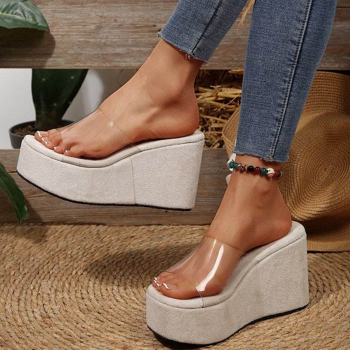 White platform sandals worn with clear soles on a wooden floor.