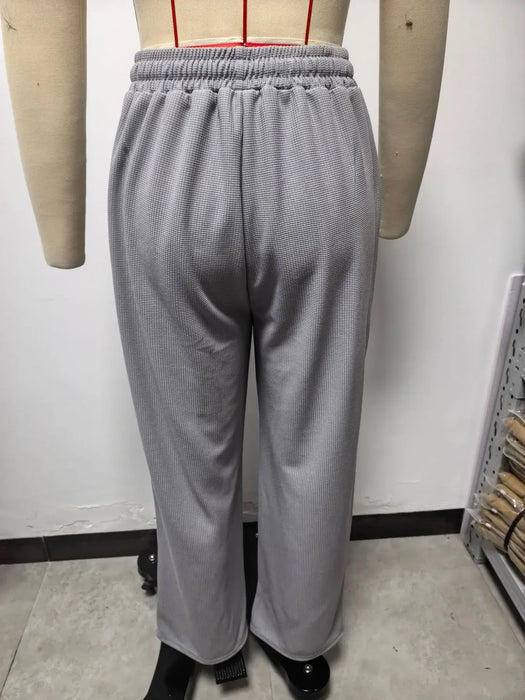 Gray sweatpants on a mannequin against a white wall.