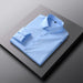 Folded light blue dress shirt on a dark surface