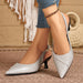 A pair of women's pointed-toe slingback pumps in a metallic silver textured finish, shown on a model's feet with blue jeans and a gold anklet against a boho-style background.