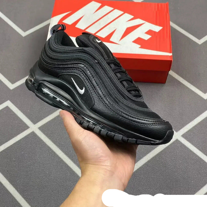 Black Nike sneaker held in a hand with a red Nike box in the background.