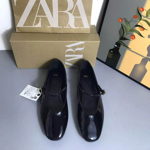 Black shoes with a Zara box on a gray surface