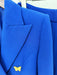 Close-up of a blue blazer with a yellow butterfly pin on a white background