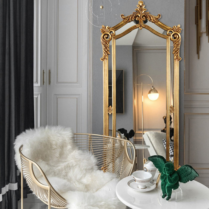 Decorative gold mirror in a stylish room with a chair and table.