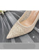 Beige high-heeled shoe with glittery texture on a gray fabric background
