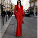 Woman in a red suit walking down a city street.