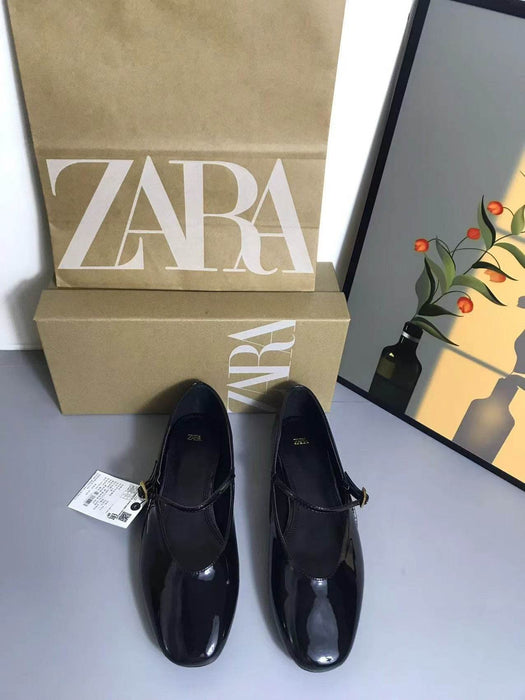 Black shoes with a Zara box on a gray surface