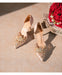 Pair of embellished high-heeled shoes next to a bouquet of red roses on a textured surface.