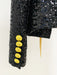 Black sequined jacket with gold buttons on a white background
