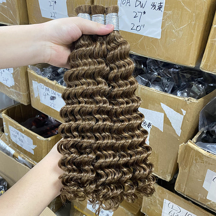 Person holding a bundle of brown hair extensions with boxes in the background