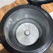 Open black pressure cooker with a silver valve on a wooden surface