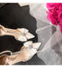 Beige high-heeled shoes with decorative bows on a dark surface with pink flowers in the background.