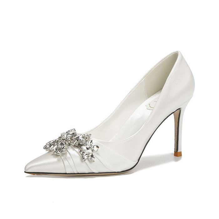 White high-heeled shoe with a decorative brooch on a white background