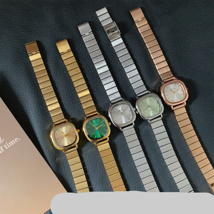 Five women's metal link watch bands with matching watch faces are arranged on a dark textured surface. The bands are gold, silver, and rose gold, paired with gold, silver, and rose gold watch cases.