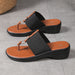 Pair of black and orange sandals on a gray floor