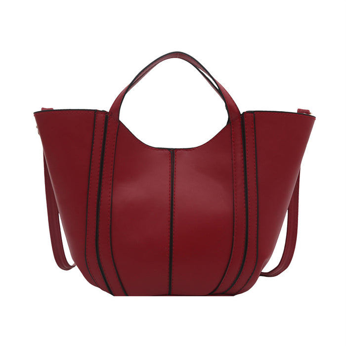 A structured red leather hobo-style tote bag with vertical black piping details and double top handles, shown against a plain white background.