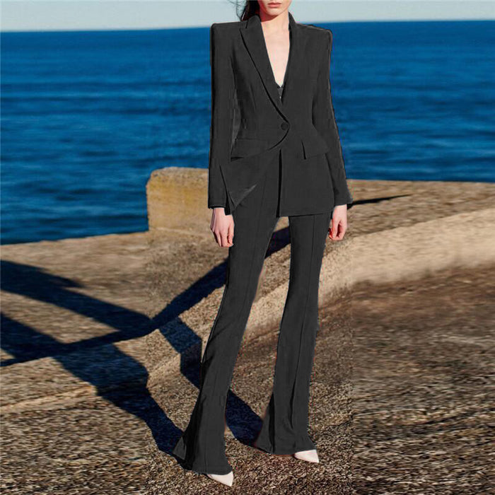 Person wearing a black suit standing on a stone ledge with ocean in the background