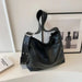 Black leather handbag on a white surface with a framed picture in the background
