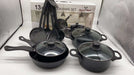 Set of black cookware with lids on a white surface, with a box labeled 'Royal Mark' in the background.
