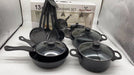 Set of black cookware with lids on a white surface, with a box labeled 'Royal Mark' in the background.