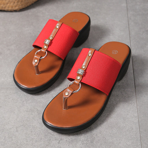 Red sandals with brown soles on a gray surface