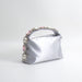Silver handbag with decorative handle on a white background