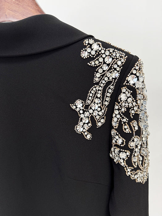 Black garment with intricate white embroidery on a plain background